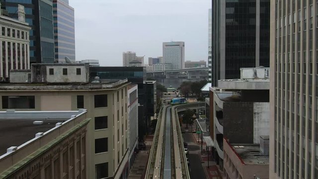 Aerial of Jacksonville Skyway train traveling between buildings arriving at station