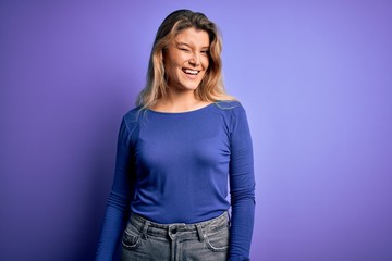 Young beautiful blonde woman wearing casual t-shirt over isolated purple background winking looking at the camera with sexy expression, cheerful and happy face.