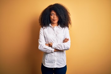 Young beautiful african american elegant woman with afro hair standing over yellow background skeptic and nervous, disapproving expression on face with crossed arms. Negative person.