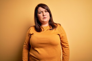 Obraz premium Beautiful brunette plus size woman wearing casual sweater over isolated yellow background skeptic and nervous, frowning upset because of problem. Negative person.