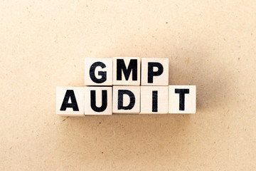 Letter block in word GMP (Abbreviation of good manufacturing practice) audit on wood background