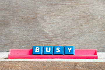 Tile letter on red rack in word busy on wood background