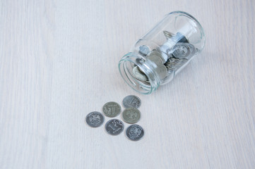 Coins and a glass jar on the table. The concept of investment, interest
