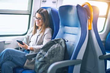 Young beautiful woman smiling happy and confident. Sitting with smile on face using smartphone travelling by train