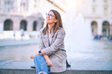 Fototapeta premium Young beautiful woman smiling happy and confident. Sitting with smile on face at the town street