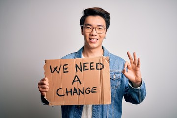 Young handsome chinese activist man protesting asking for change holding poster doing ok sign with fingers, excellent symbol