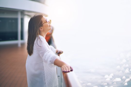 Young beautiful woman on vacation smiling happy and confident. Standing on a deck of ship with smile on face doing a cruise