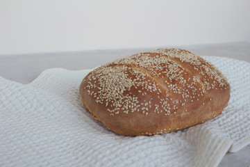 Freshly baked homemade kefir bread with sesame seeds on selfisolation. Bun on a kitchen napkin.