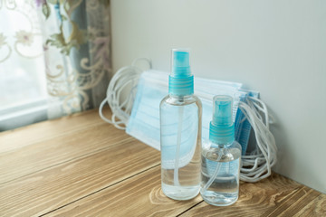 Coronavirus protection. Hand sanitizer bottle and medical protective surgical masks on table.