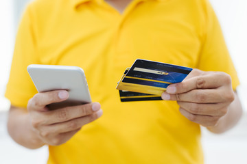 the young man wears a yellow shirt holding blank white credit card mockup. Plain creditcard mock up...