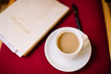 Coffee Up on Red Background with a Gold Notebook and a Pen.