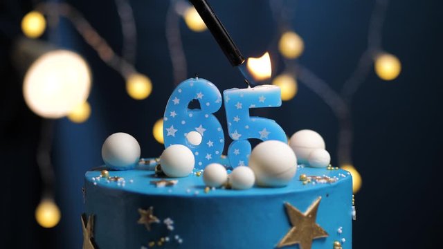 Birthday cake number 65 stars sky and moon concept, blue candle is fire by lighter and then blows out. Copy space on right side of screen if required. Close-up and slow motion