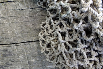 background macro image of a braided fishing net with large meshes on an old gray cracked tree