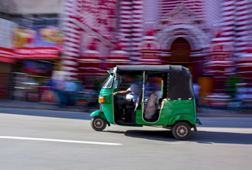 Abstracted Panning Photography Of A Three Wheeler In Front Of Red Mosque In Colombo, Sri Lanka. Tuk Tuk Can Be Found On All Roads In Sri Lanka That Transporting Locals, Foreigners, Or Freights