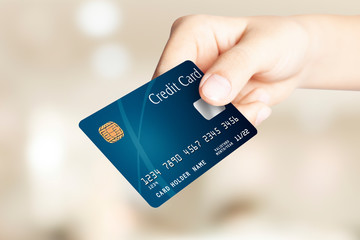 Close up hand holding and showing blue mockup credit card, front side view, against on defocus blur light background. shopping concept