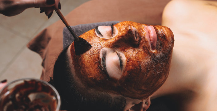 Caucasian woman having a facial care treatment with a cacao mask applied at the spa salon