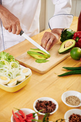 Mature man cutting vegetables when cooking delicious salad for lunch at home