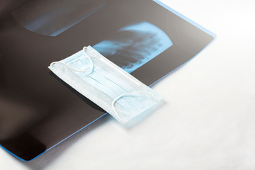 Protective medical face mask with X-ray scan (film) of the lungs on white background. Coronavirus,...