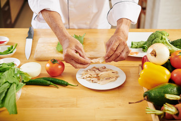 Man wrapping boiled chicken fillet in lettuce leaves