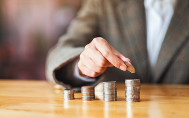 Businesswoman holding and stacking coins on the table for saving money concept