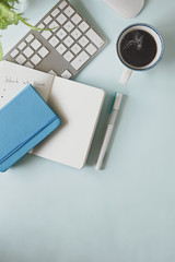 Top view of comfortable worksapce. Computer laptop, hot coffee cup, marker pens, notebook, diary, flowers in a glass vase flat lay on working desk.