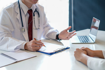 Doctor man talking to patients while filling up an application form in the hospital about medical treatment.