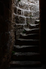 The stairs in the dark. Part of a Gothic stone Castle. Antique stone stairs. Made steps in Rock. Wallpaper and background.