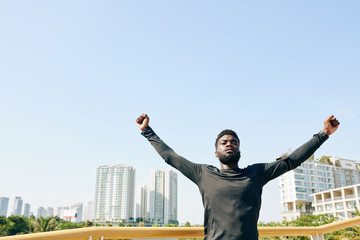 Serious young Black sportsman raising arms when doing exercise for chest opening