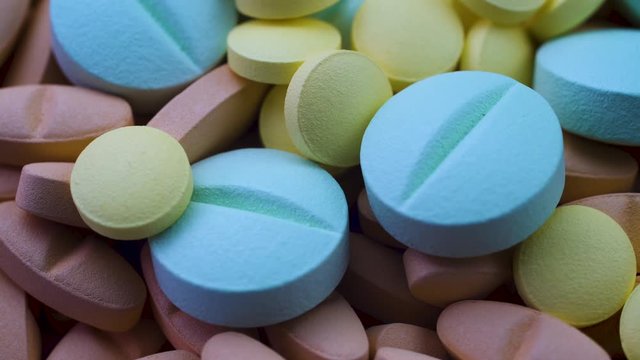 Round blue and yellow antiviral pills lie on red antibiotics. Closeup rotation