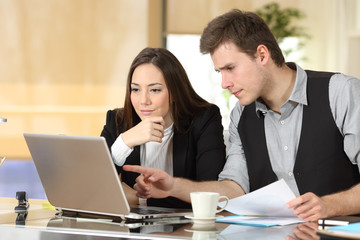 Coworkers checking laptop content together at office