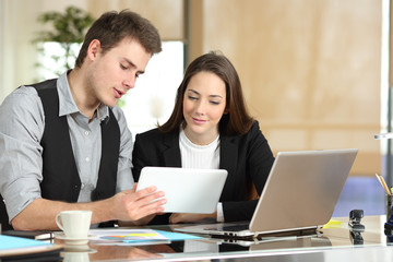 Employee helping coworker showing tablet