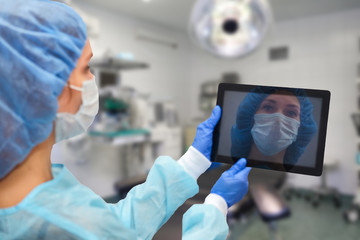 Female doctor in protective suit: medical mask, hat and robe. The woman uses a digital tablet and displays disease statistics on the screen.