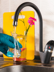 water purification specialist tap water pours into a glass flask.