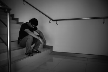 Depressed man sitting on stair of residence building. Sad man, Cry, drama, lonely and unhappy concept.