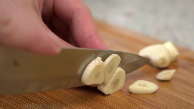 A female cook cuts garlic on a cutting board. Cooking Russian cabbage soup. A woman cuts vegetables on a cutting board. Cooking in the home kitchen.