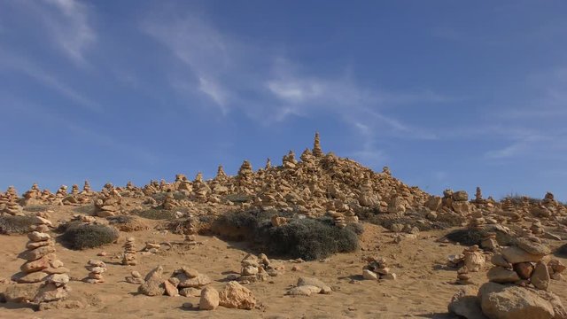 Pyramids of stones on top of a hill against the blue sky. Zoom out.