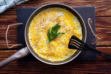 close up. home omelet with herbs in pan on wooden.