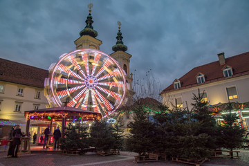 Ferris wheel and Christmas trees in front of Mariahilfer Church, Graz, Austria