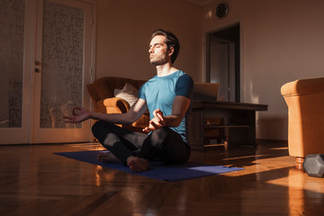 Handsome man practicing yoga in his living room, he feel peaceful and enjoying in moments