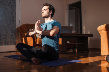 Handsome man practicing yoga in his living room, he feel peaceful and enjoying in moments