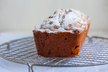 Freshly baked loaf cake with raisins on beautiful table. Garnished with powder sugar. 
