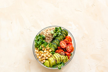 Veggie bowl. Vegetable salad with quinoa, avocado, tomato, spinach and chickpeas - on beige table. Top view copy space