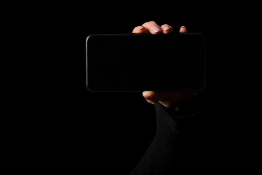 Person holding in hand smartphone with empty blank screen, photo isolated on black background