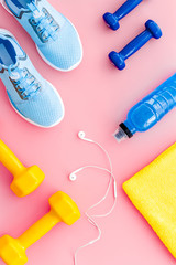 Workout flat-lay with sneakers, dumbbell, towel on pink background top-down