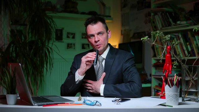 A man at the office desk smokes a vaporizer with medical marijuana. Psychological dissociation of a person in self-isolation.