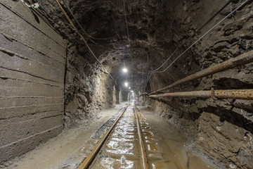 Fototapeta na wymiar Underground gold mine tunnel with rails and light