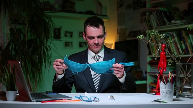 A man examines a female bra at the table. Closed flirt. A kind of courtship, indicating a certain opportunity or expectation of a relationship.