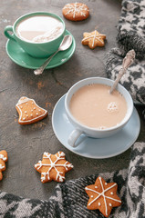 Cups with tea blue and green. On a gray concrete background. Next to them are Christmas cookies and woolen cloth. Vertical photo. View from above.