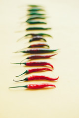 Chilli peppers assorted by colour on yellow backdrop
