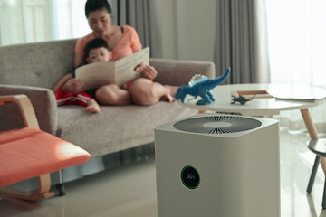 air purifier in living room with mother and kid reading inside home